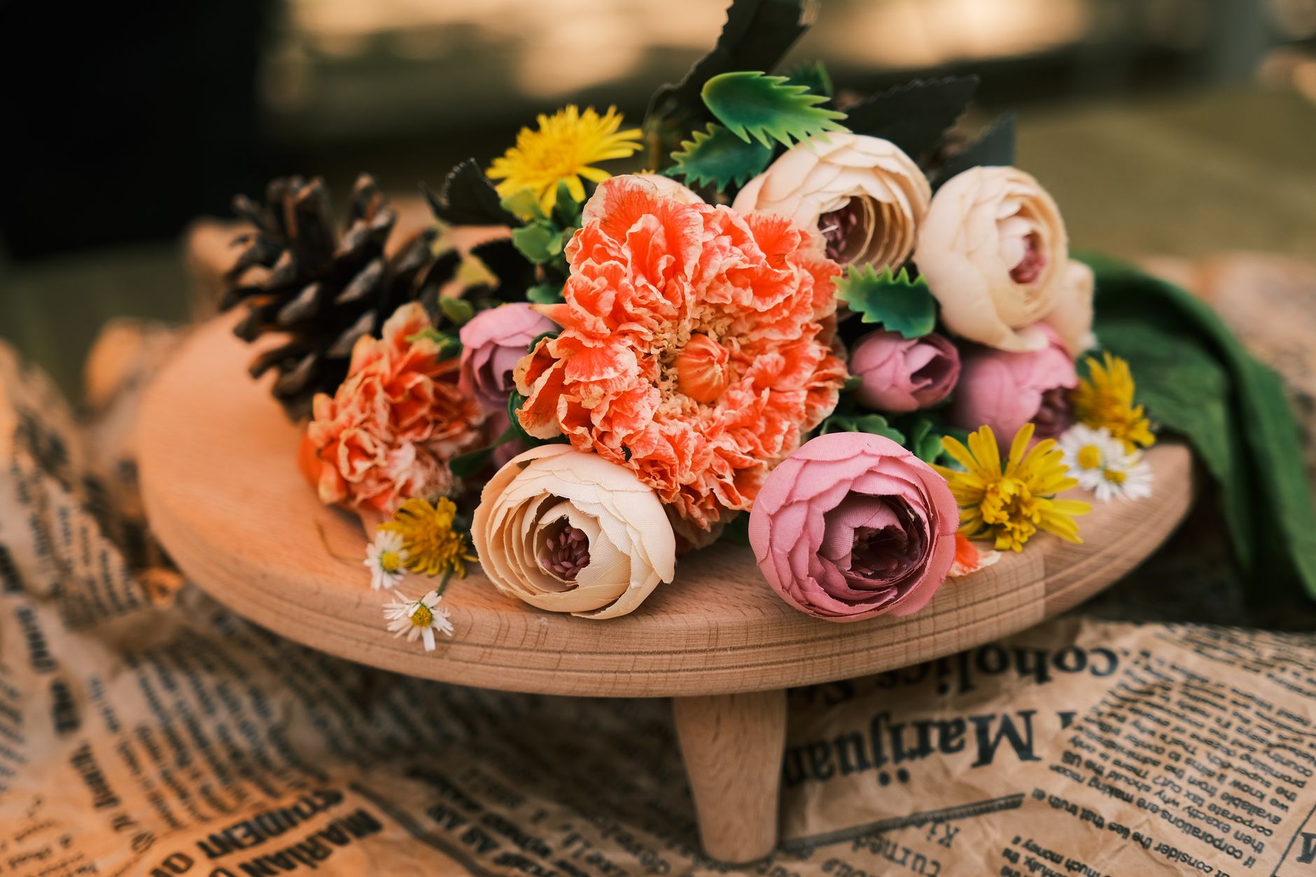 A hand-tied bouquet of pink peonies and ranunculus on a wooden stand